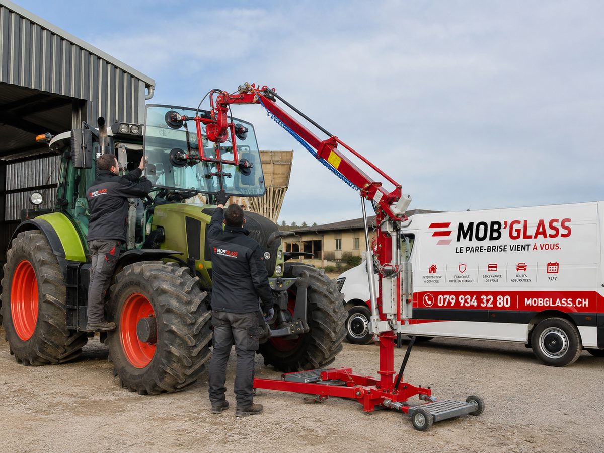 Remplacement du pare-brise d'un tracteur agricole Claas dans la cour d'une exploitation, avec potence de levage à ventouses et deux poseurs Mob'Glass
